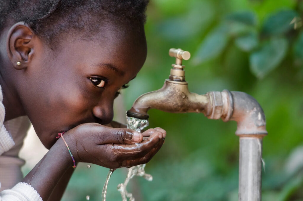 Haitian girl drinking water from faucet